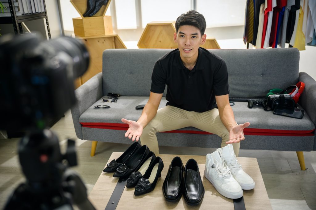 Social media influencer reviewing fashion shoe. Smiling young man vlogging