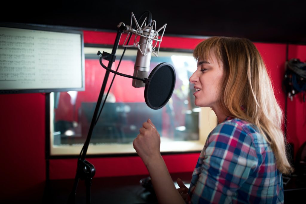 Young singer woman during music session at recording studio